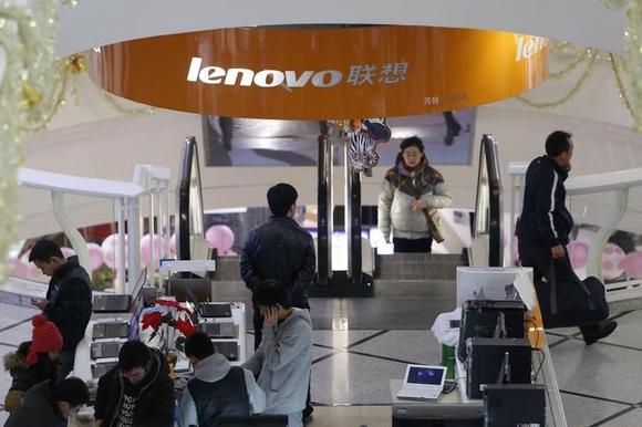 People stand under a sign showing the Lenovo company at a computer market in Shanghai January 21, 2014. REUTERS/Aly Song