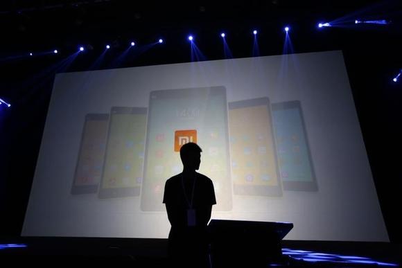 A security guard stands in front of a screen showing Xiaomi mobile phones ahead of the launching ceremony of Xiaomi Phone 4, in Beijing, July 22, 2014. REUTERS/Jason Lee