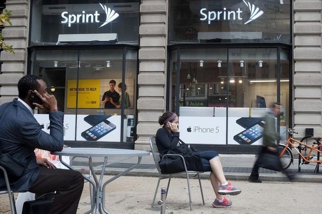 People talk on their cell phones as passers-by walk past a Sprint store in New York, October 15, 2012. REUTERS/Keith Bedford