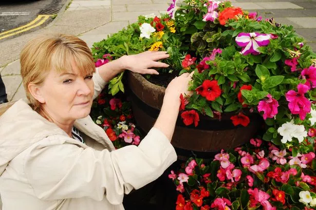 Ann Higgins examines the damage after vandals pulled flowers out of tubs in the centre of Eston