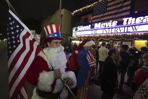 Matt Ornstein, dressed in a Santa Claus costume, holds an American flag as fans line up at the Silent Movie Theatre for a midnight screening of 'The Interview' in Los Angeles, California December 24, 2014. REUTERS/Jonathan Alcorn